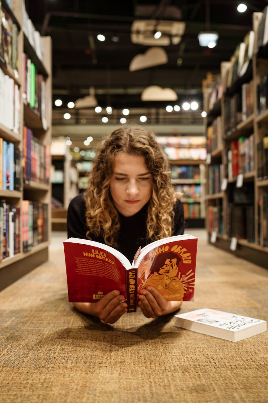Dievča si listuje v kníhkupectve knihu Lujza mimo obrazu.